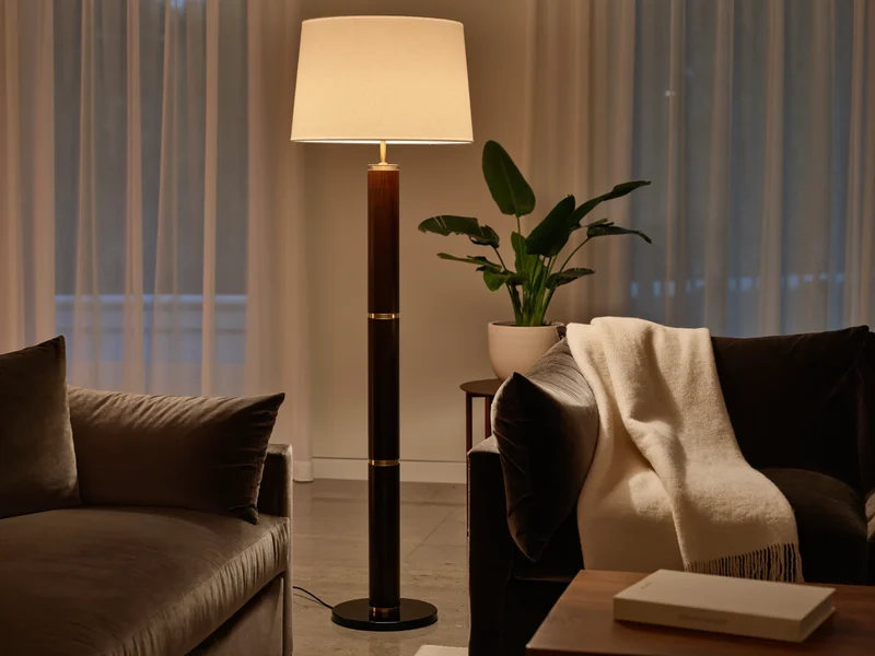 Gemütlicher Abendraum mit warmem Lampenlicht auf Sofa, Pflanze und Buch